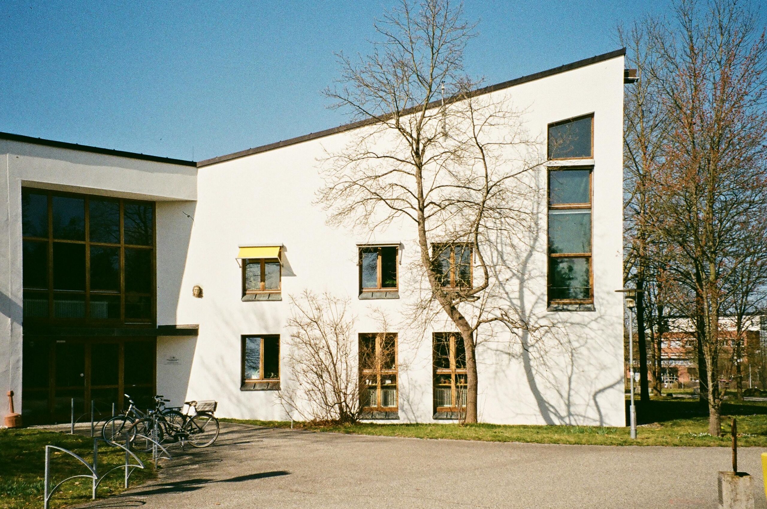 Contemporary building facade with bicycles parked outside on a sunny day in Bayreuth, Germany.